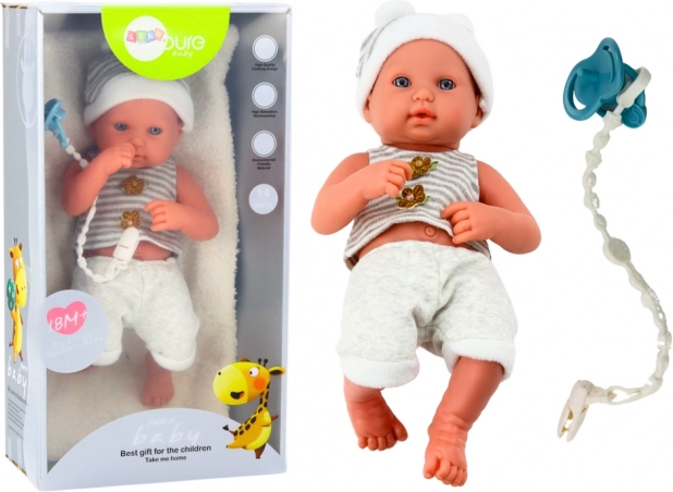 Realistische babypop in wit‑grijze outfit met lus voor speen en dekentje